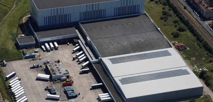 Aerial view of Lineage’s Grimsby cold storage and port facility in the UK, featuring loading bays, solar panels and refrigerated trailers.