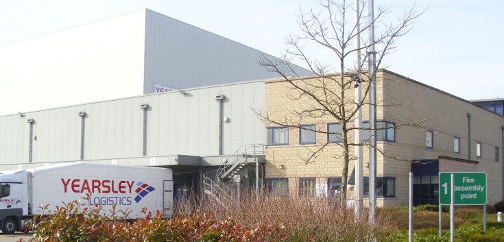 Front view of Lineage’s Hams Hall automated cold storage facility in Coleshill, UK, with a Yearsley Logistics truck and Fire Assembly Point sign.