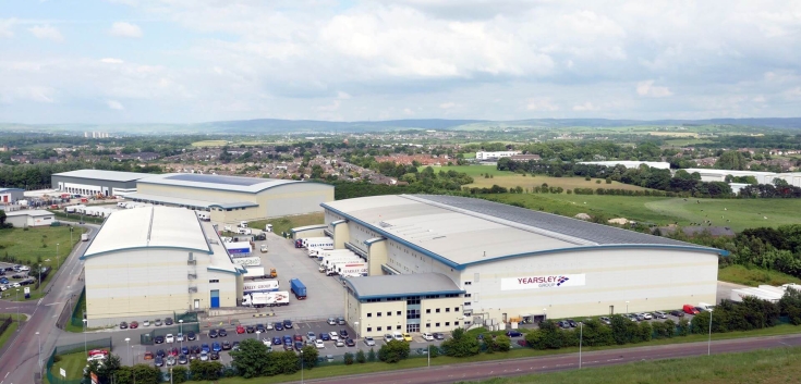 Aerial view of Lineage’s automated cold storage warehouse in Heywood, UK, with Yearsley Group trucks and multiple buildings across a large logistics site.