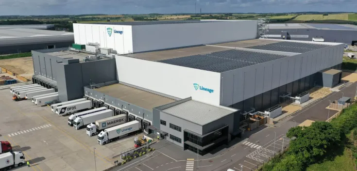 Vista aérea del almacén frigorífico de Lineageen Peterborough con paneles solares en el tejado, rodeado de modernos edificios industriales y carreteras.