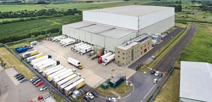 Aerial view of Lineage’s Wisbech – Boleness automated cold storage warehouse in the UK, with multiple trucks at the loading docks.
