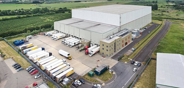 Vista aérea del almacén frigorífico automático de Lineage en Wisbech - Boleness, Reino Unido, con varios camiones en los muelles de carga.