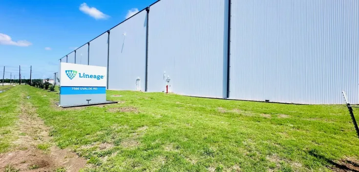Exterior of Lineage’s Cold Port facility in Houston, Texas, showing the large white warehouse wall and the Lineage sign along the grassy front lawn on a clear day.