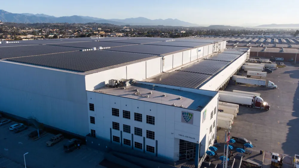 Vista aérea de unas instalaciones de Lineage en la que se aprecian los amplios paneles solares de la azotea, los remolques atracados y las montañas visibles al fondo.