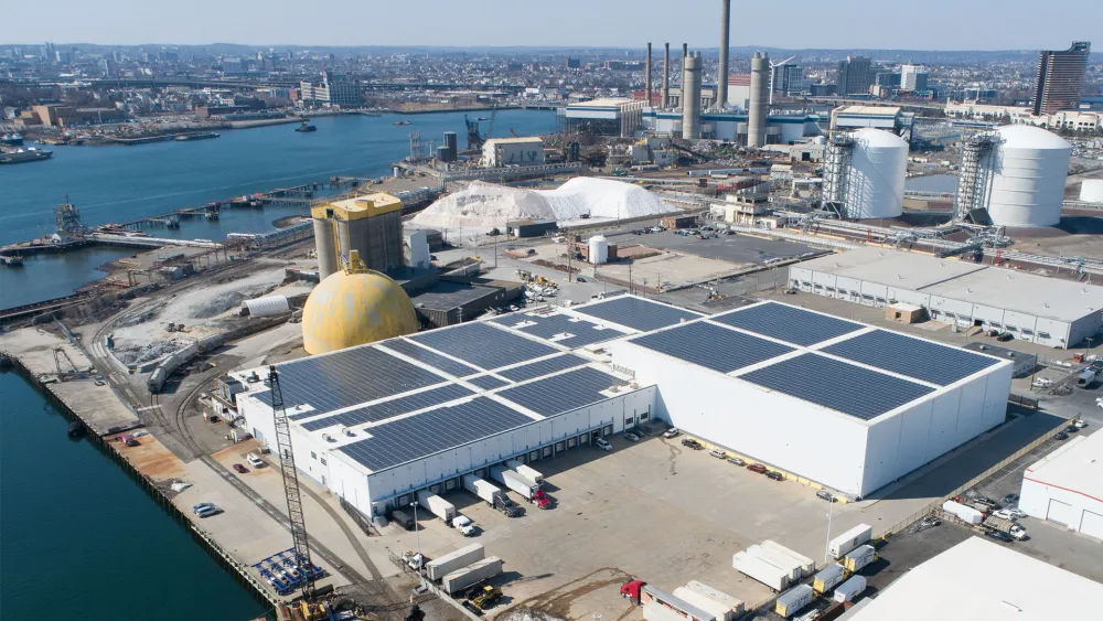 An industrial building seen from above, situated near a substantial body of water.