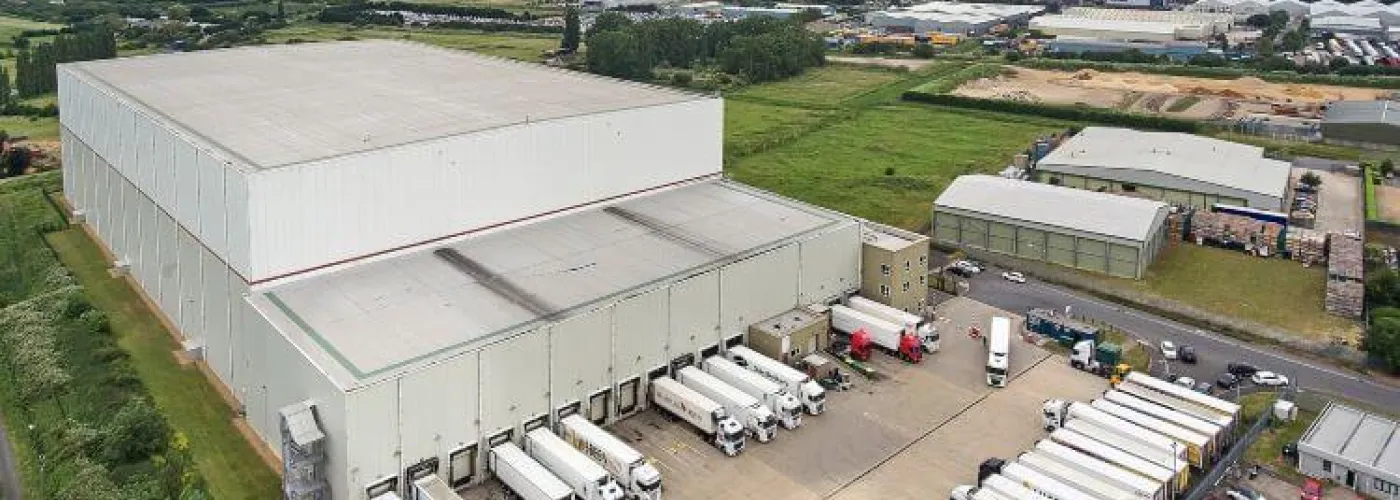 Amplia toma aérea del almacén frigorífico de Lineageen Wisbech (Boleness), rodeado de campos de cultivo y naves industriales, con remolques haciendo cola en los muelles.