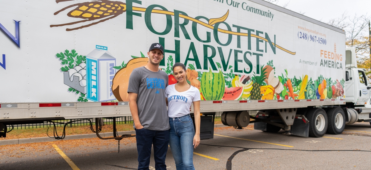 Detroit Lions quarterback Jared Goff and his fiancé, Christen Harper, stand in front of a Forgotten Harvest semi trailer at a food distribution event in Detroit