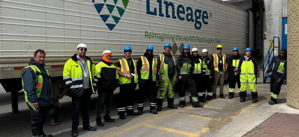 Miembros del equipo de almacén de Calgary Great Plains juntos delante de un remolque de Lineage , mostrando una sólida cultura de seguridad y unidad de equipo.