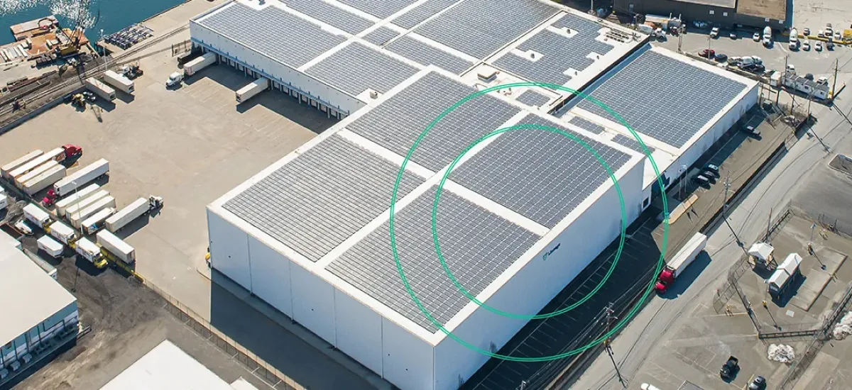 Aerial view of a Lineage cold storage facility in the Northeast U.S. featuring rooftop solar panels, with nearby highways and port infrastructure visible in the background.