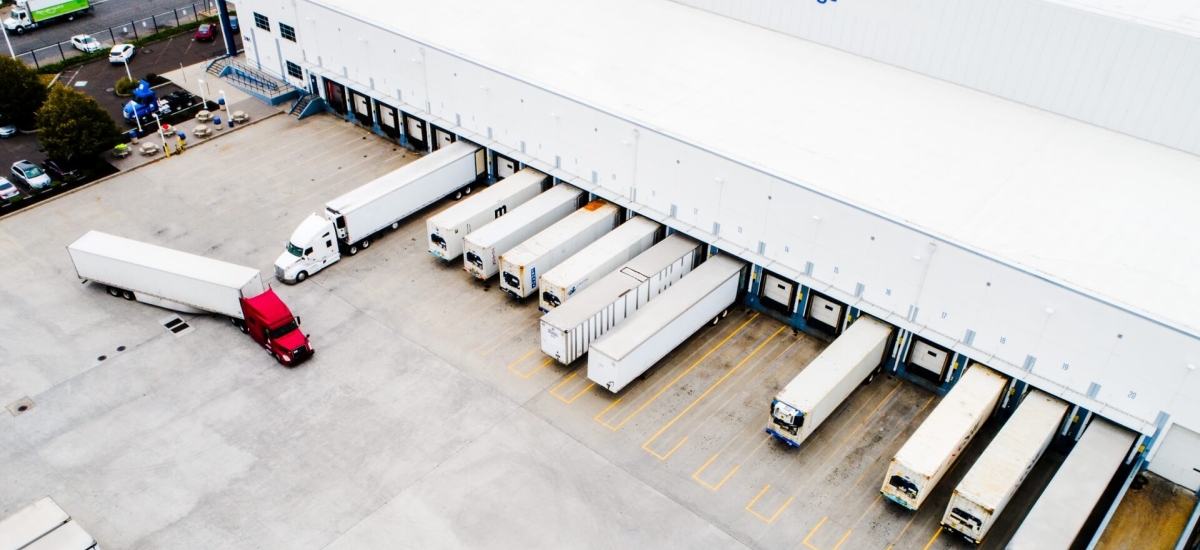 Aerial view of refrigerated trucks loading and unloading at a Lineage warehouse, showcasing foodservice distribution and cold chain operations.