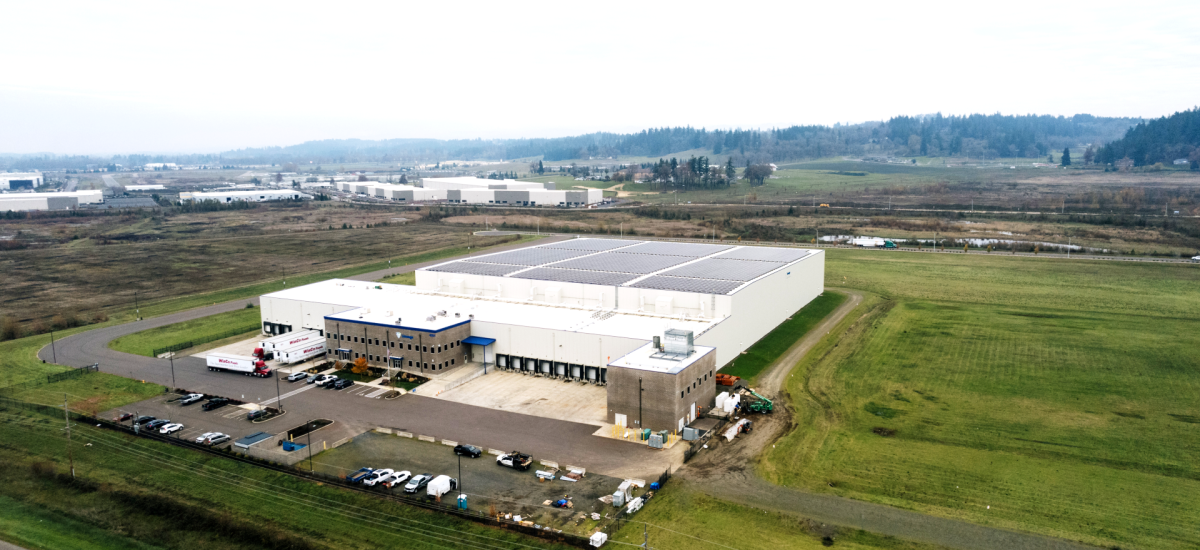An aerial view of Lineage's cold storage warehouse in Salem, OR shows the building has solar panels on the roof
