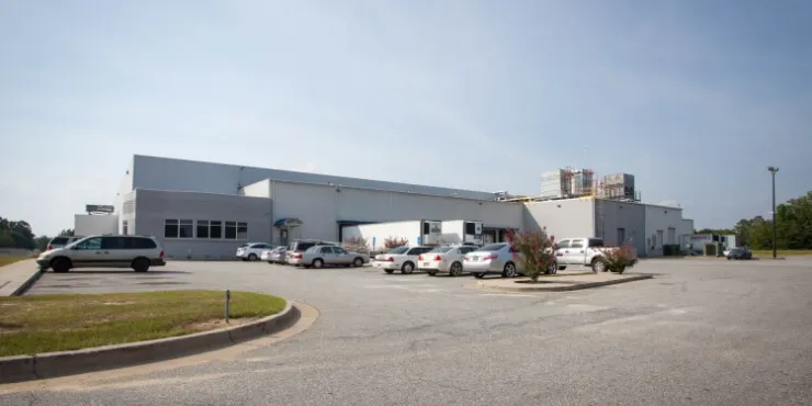 Vista exterior del almacén frigorífico de Lineageen Macon, Atlanta, Georgia, con un almacén blanco con muelles de carga, perímetro vallado y una pequeña zona de oficinas.