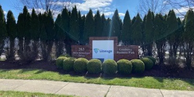 Imagen exterior Letrero Lineage detrás de arbustos