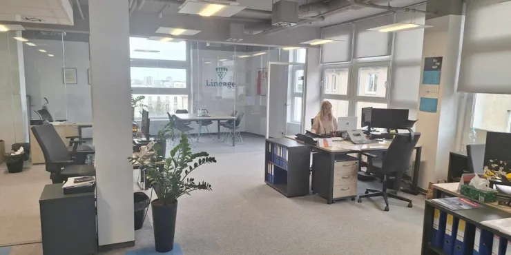 Moderno espacio de oficinas de Lineage en Gdynia (Polonia), con un espacio de trabajo abierto con mesas, ordenadores y una sala de conferencias con paredes de cristal, para apoyar las operaciones de expedición de mercancías y logística.