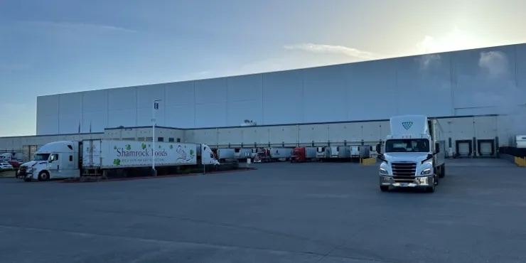 Almacén frigorífico de Lineage en Pasco, Washington, con múltiples muelles de carga, camiones aparcados y un gran patio pavimentado al amanecer, que favorece la eficacia de las operaciones de la cadena de frío.