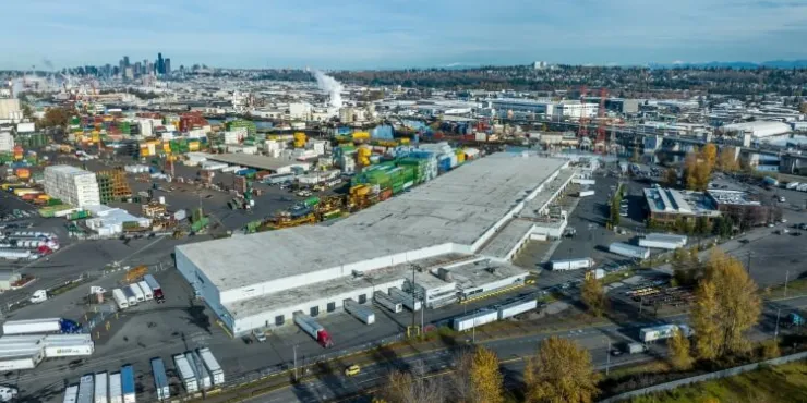 Vista aérea de las instalaciones de Lineageen Seattle-Michigan con el horizonte de Seattle al fondo, destacando su ubicación estratégica cerca de la logística portuaria y urbana.