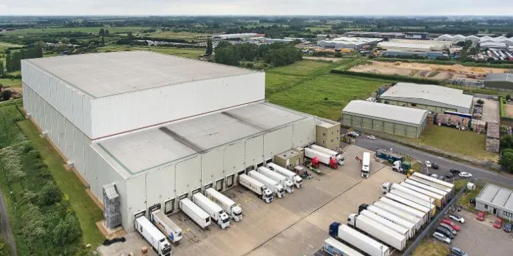 Amplia toma aérea del almacén frigorífico de Lineageen Wisbech (Boleness), rodeado de campos de cultivo y naves industriales, con remolques haciendo cola en los muelles.