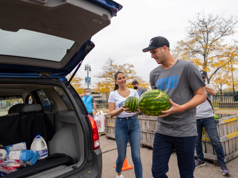 NFL Player Jared Goff holds fresh fruit as he loads a vehicle during a food donation event in Detroit