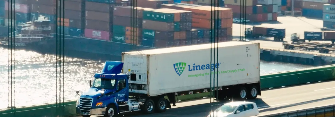 A Lineage truck crossing a bridge with a port full of shipping containers in the background, representing supply chain solutions for navigating tariffs and global trade challenges.