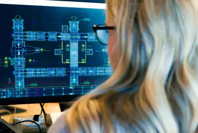 A female data scientist wearing glasses works at her computer; the screen shows a codigital simulation