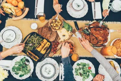Top view of a family-style dinner table with roasted turkey, grilled vegetables, fresh salads, bread, and fruits, highlighting the theme of togetherness and food sharing for World Food Day.