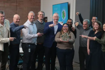 Swemy Sanchez Roman, holding her Servant Leader for Good award, beams with pride as her colleagues at Lineage celebrate her achievement, pointing and smiling in recognition of her dedication to community service and leadership.