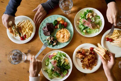 Plates of food arranged on a table as hands reach in to eat