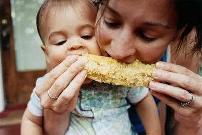 A mother and child share corn on the cob