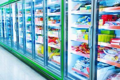 Allée d’aliments surgelés avec congélateurs à portes vitrées remplis de produits emballés, représentant les besoins d’entreposage de la chaîne du froid et de traçabilité des aliments.