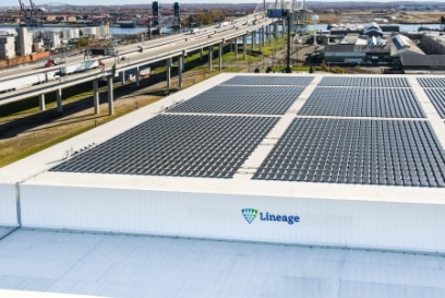 Aerial view of a Lineage cold storage facility in the Northeast U.S. featuring rooftop solar panels, with nearby highways and port infrastructure visible in the background.