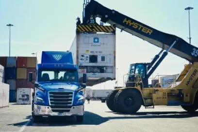 Refrigerated Lineage truck transporting shipping container at a port terminal with cargo handling equipment supporting bonded drayage operations.