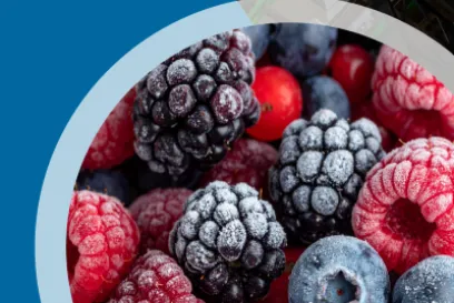 Frozen berries - raspberries, blackberries, and blueberries - cropped in a circle on a blue background