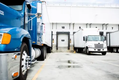 Refrigerated trucks at loading docks outside a Lineage cold storage warehouse.