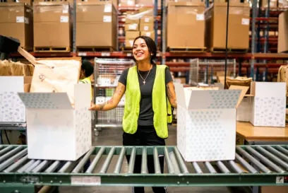 Lineage team member working at a direct-to-consumer fulfillment station with packaged orders and boxes moving along a conveyor.
