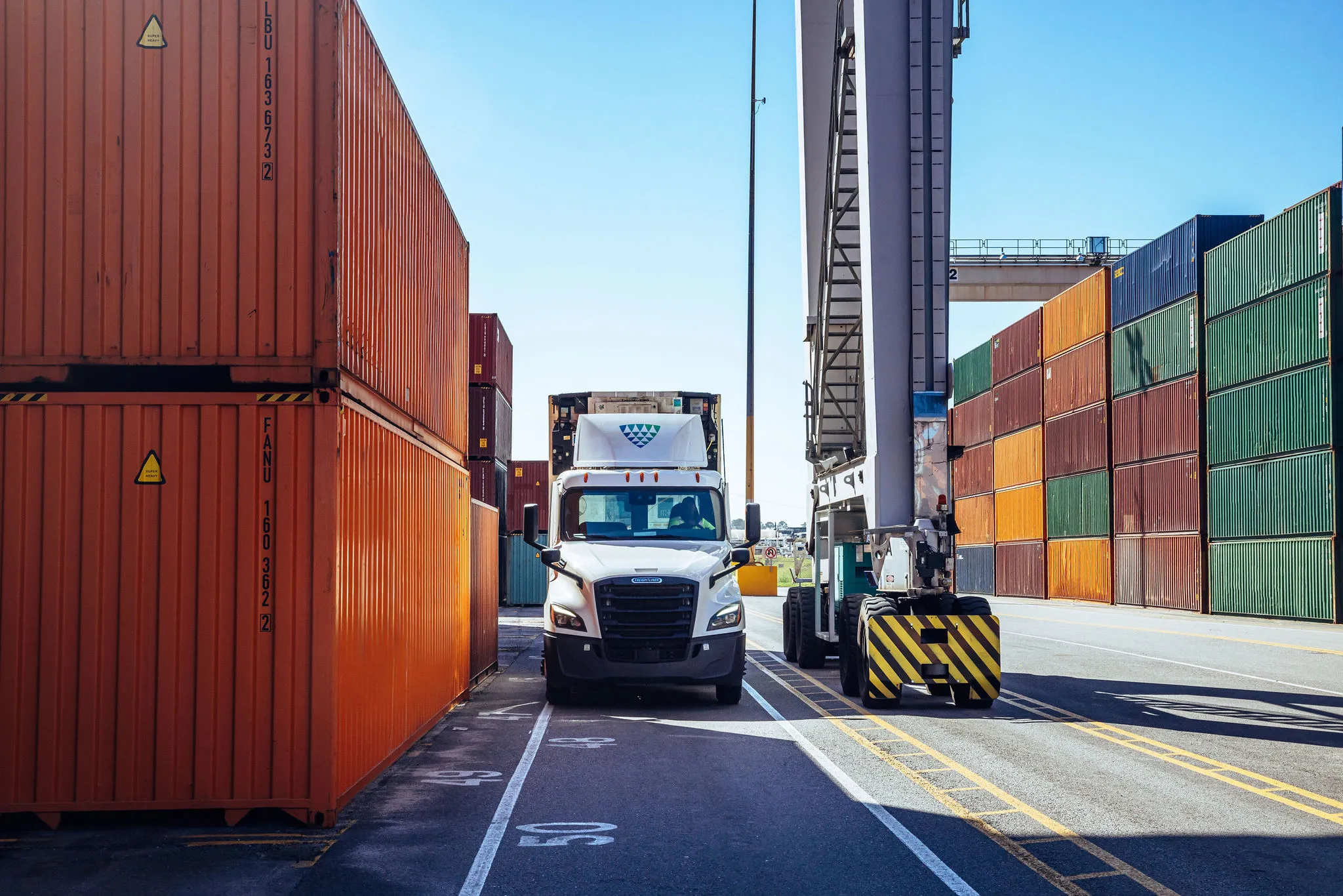 A truck parked beside a shipping container at a port.