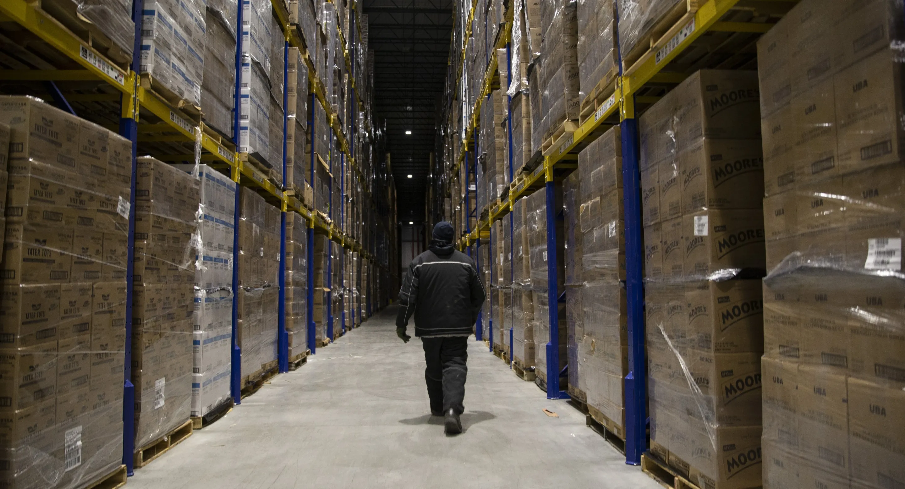Man walking down an aisle at a Lineage cold warehouse