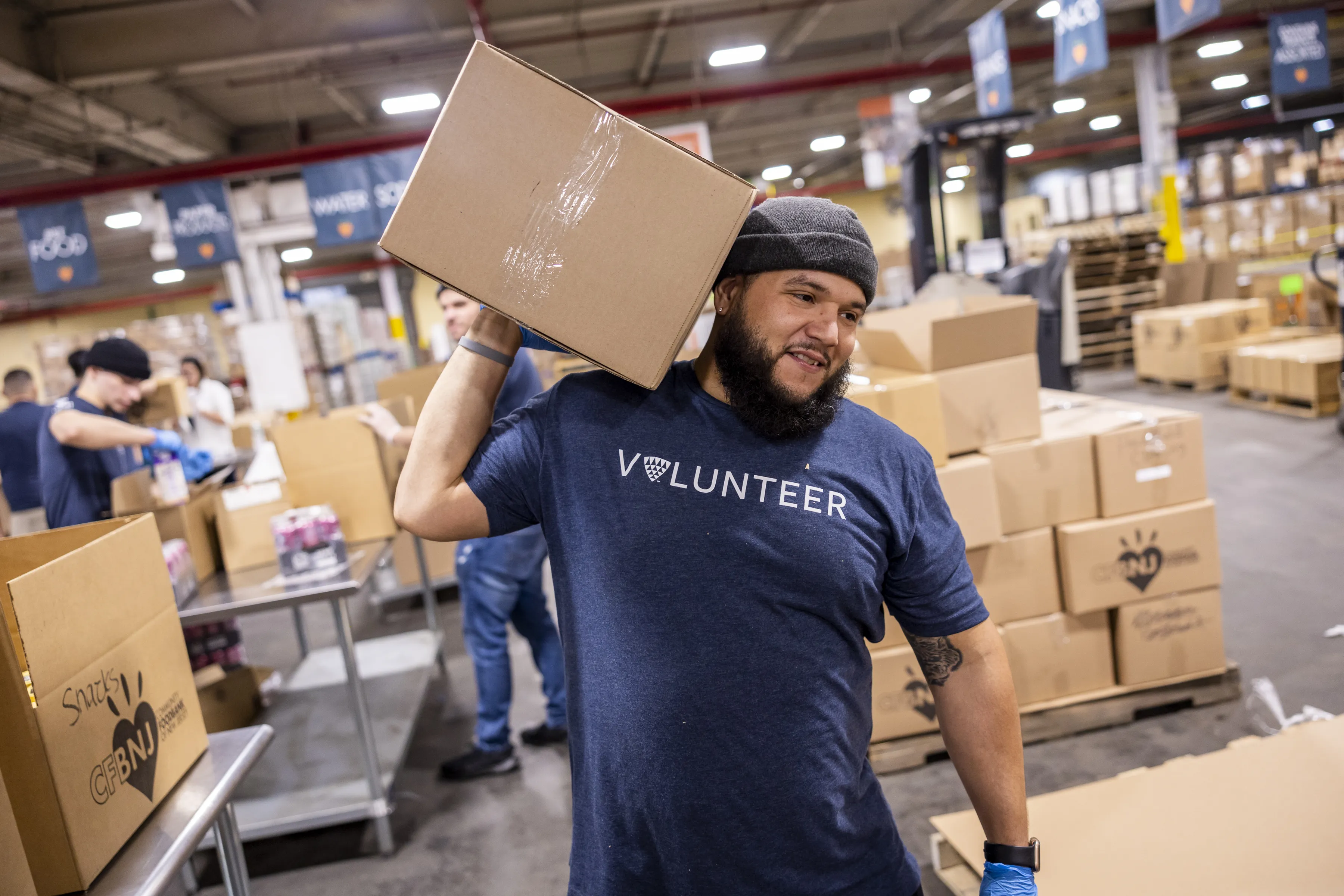 Hombre con camiseta de Voluntario viviendo una caja en un acto de Foundation for Good