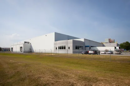 Vista exterior del almacén frigorífico de Lineageen Macon, Atlanta, Georgia, con un almacén blanco con muelles de carga, perímetro vallado y una pequeña zona de oficinas.