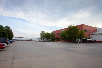 Vue extérieure de LineageMcDonough - Entrepôt frigorifique du 200 King Mill, doté d’un immeuble de bureaux en briques rouges, d’un stationnement spacieux et de plusieurs camions à quai.