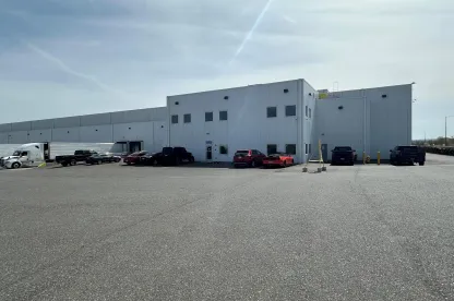 Vista exterior del almacén frigorífico de Lineage en Pasco, Washington, con una moderna instalación blanca con camiones aparcados, coches y un amplio terreno para operaciones logísticas.