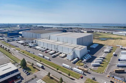 Vue aérienne de Lineage's Bergen op Zoom, installation d’entreposage frigorifique aux Pays-Bas, comprenant plusieurs quais de chargement et camions réfrigérés pour le factage et la distribution.
