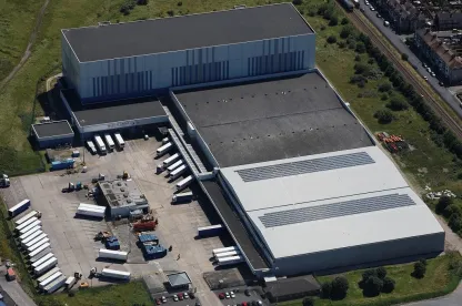 Vista aérea de las instalaciones portuarias y de almacenamiento frigorífico de Lineageen Grimsby (Reino Unido), con muelles de carga, paneles solares y remolques frigoríficos.