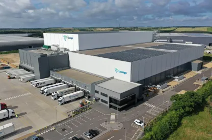 Vista aérea del almacén frigorífico de Lineageen Peterborough con paneles solares en el tejado, rodeado de modernos edificios industriales y carreteras.