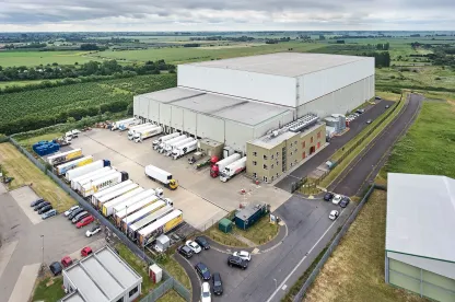 Vue aérienne de LineageEntrepôt frigorifique automatisé Wisbech – Boleness au Royaume-Uni, avec plusieurs camions sur les quais de chargement.