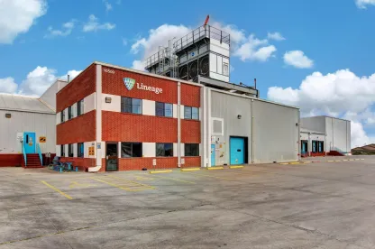 Extérieur de la Lineage installation de stockage frigorifique à El Paso, Texas, montrant l’immeuble de bureaux en brique, les baies d’entrepôt et le terrain pavé sous un ciel dégagé.