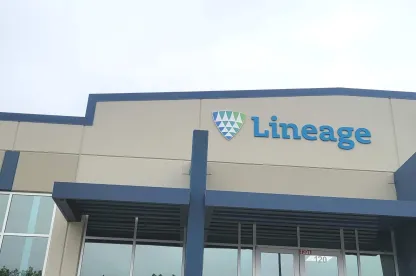 Entrada principal de las instalaciones de Lineageen Lancaster, Texas, mostrando la fachada azul del edificio, la señalización del logotipo y la entrada de cristal en un día nublado.