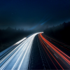 Lights racing down highway at night.