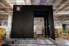 A neatly stacked pallet positioned on a Lineage Eye conveyor system in a clean, well-organized, automated cold storage warehouse, with safety guardrails and scanning stations in the vicinity.